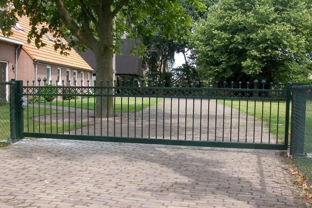 Groene stalen schuifpoort bij een erf